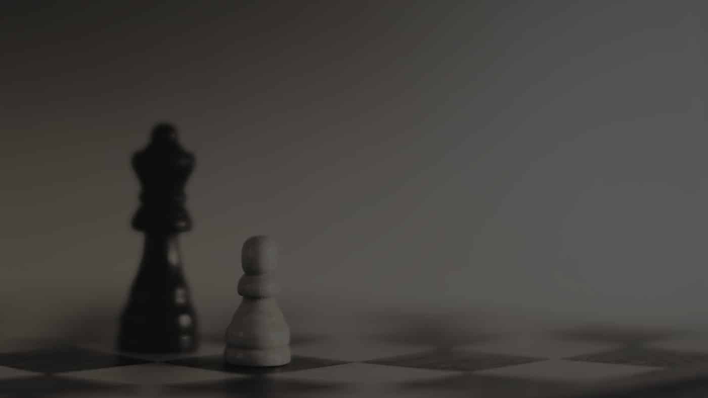 An grey overlayed picture of two chess items, the Queen & a pawn.